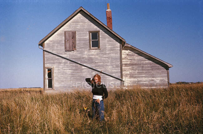 Una donna in piedi in un campo di fronte a una casa — Foto stock