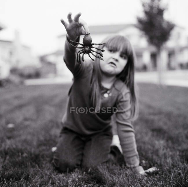 Une fille tenant une fausse araignée — Photo de stock