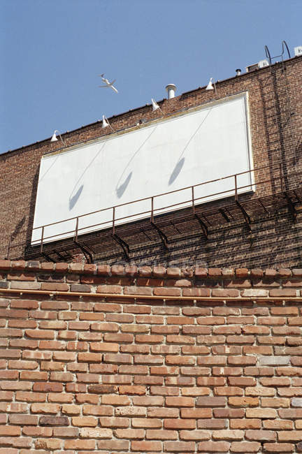 Vista de alto ângulo da fachada de construção com painel em branco pendurado — Fotografia de Stock