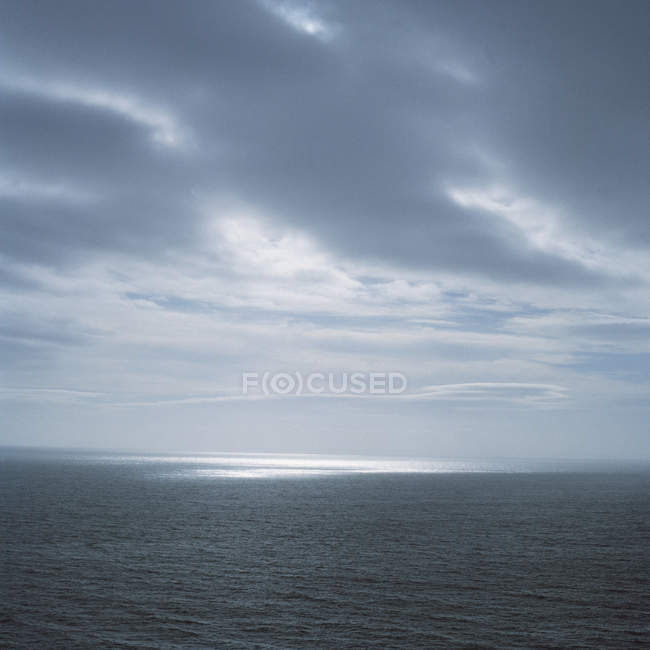 Nuvole scure sulle onde oceaniche con macchie di luce — Foto stock
