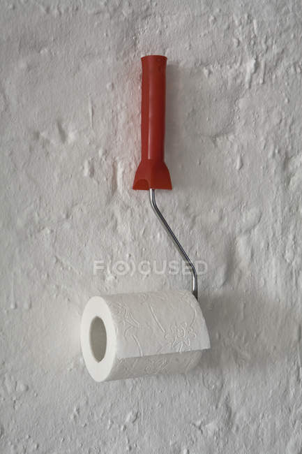 Papel higiénico colgado en rodillo de pintura unido a la pared - foto de stock