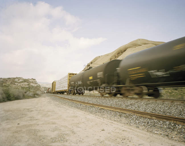 Freight train in motion at rocky landscape — Stock Photo