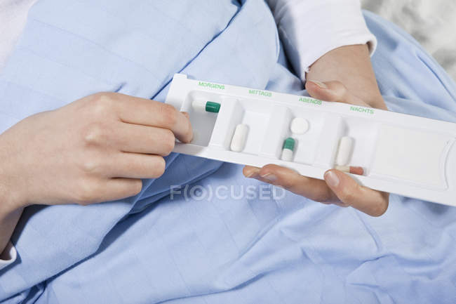 Coltivare mano paziente prendendo pillola da un organizzatore pillola — Foto stock