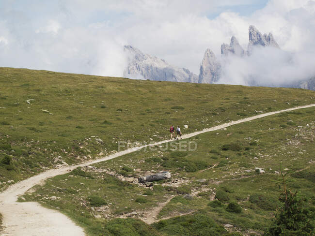 Backpackers escursioni attraverso il paesaggio erboso e montagne — Foto stock