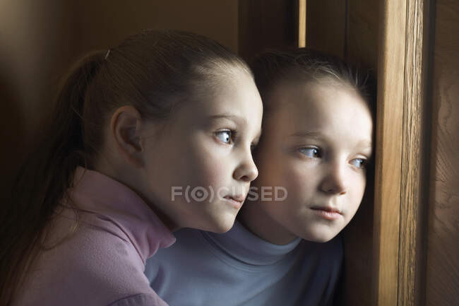 Dos chicas escuchando a escondidas en la puerta, de cerca - foto de stock