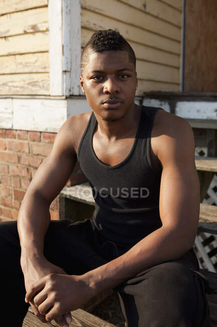 Retrato de un joven sentado frente a una casa - foto de stock