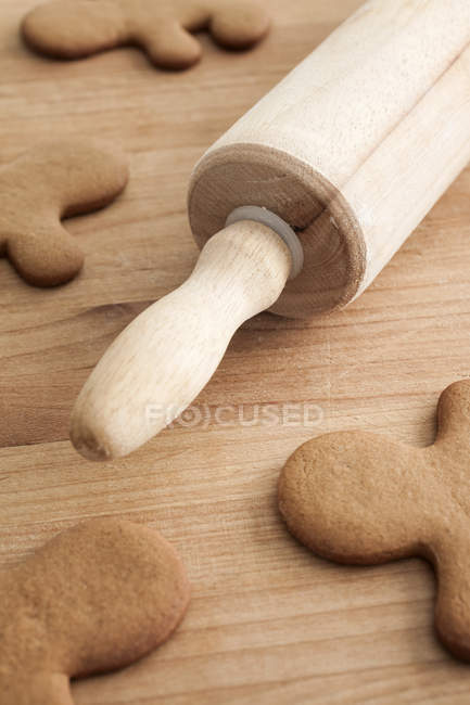 Unfrosted gingerbread men on wood table with rolling pin, close-up — Stock Photo