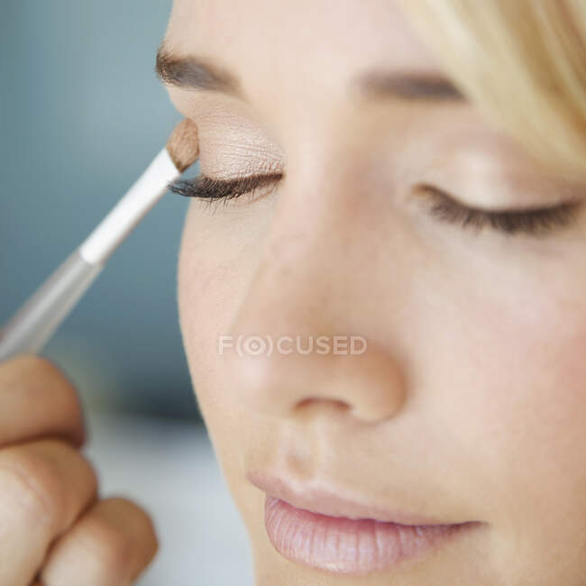 Detalle de una joven aplicando sombra de ojos - foto de stock