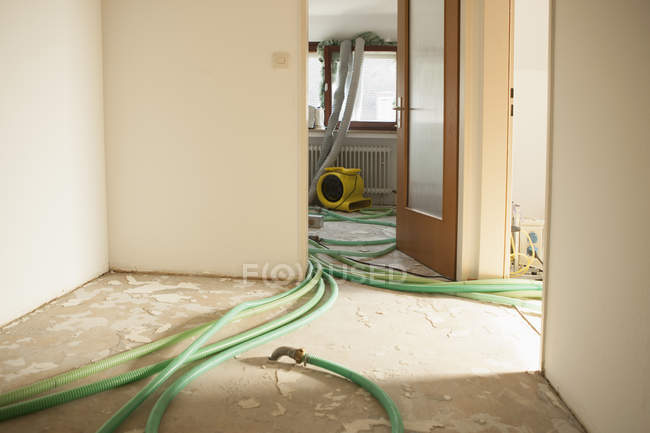 Green Hoses On Floor In Room Under Renovation Machine Part Door Stock Photo