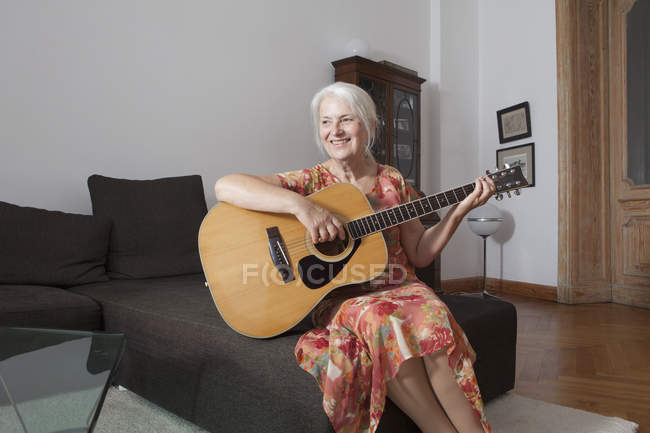 Старші жінки гри на гітарі у вітальні на дому — стокове фото