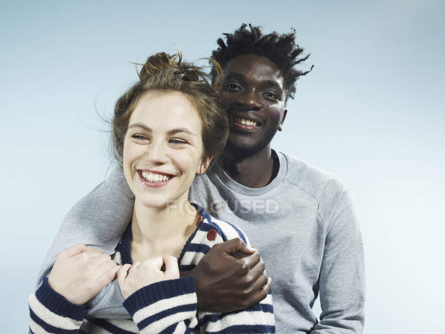 Sorridente giovane uomo che abbraccia sorridente ragazza su sfondo blu — Foto stock