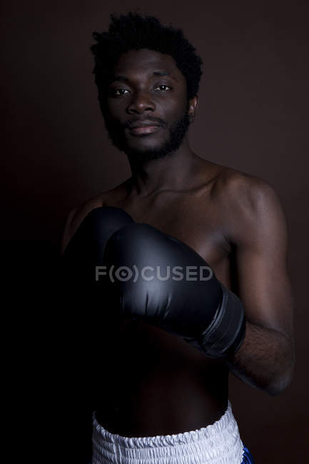 A serious young man posing in boxing shorts and boxing gloves — Stock Photo