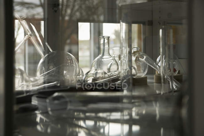 Varios artículos de vidrio de laboratorio en los estantes - foto de stock