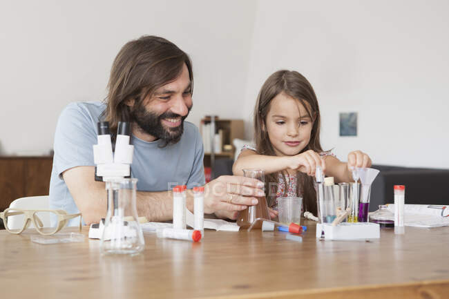 Батько і дочка працюють над науковим проектом вдома. — стокове фото