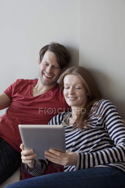 Smiling Couple using digital tablet on sofa at home — Stock Photo