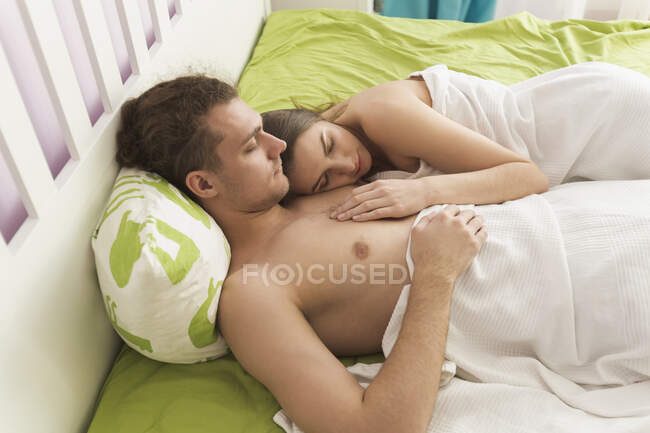 Vista de ángulo alto de la pareja sin camisa durmiendo en la cama - foto de stock