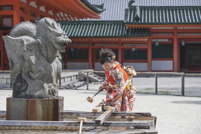 Взрослая женщина омывает руку над храмом — стоковое фото