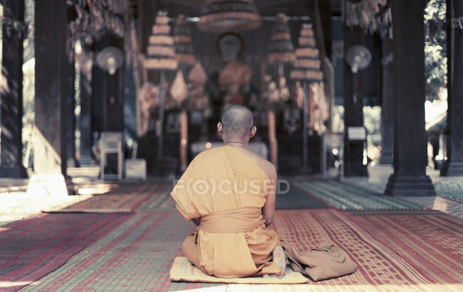 Rear view of monk sitting in front of oriental altar — Stock Photo