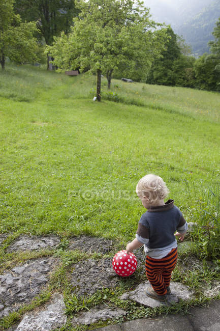 Bambino ragazzo che gioca con la palla sul prato in natura — Foto stock