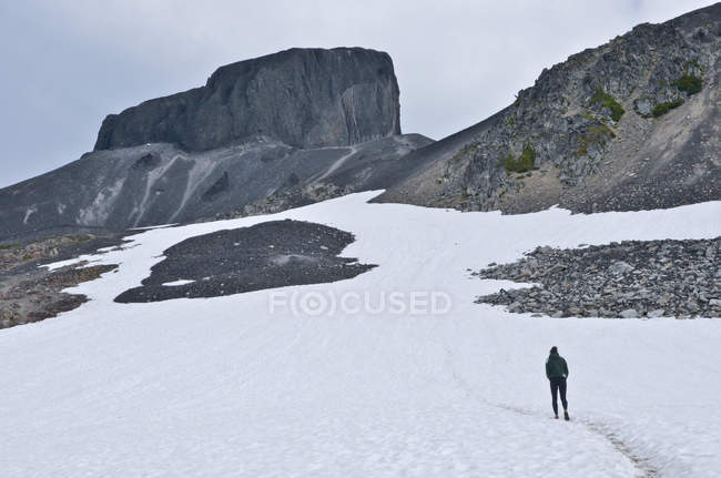Vista trasera del excursionista al caminar en terreno de montaña de invierno - foto de stock