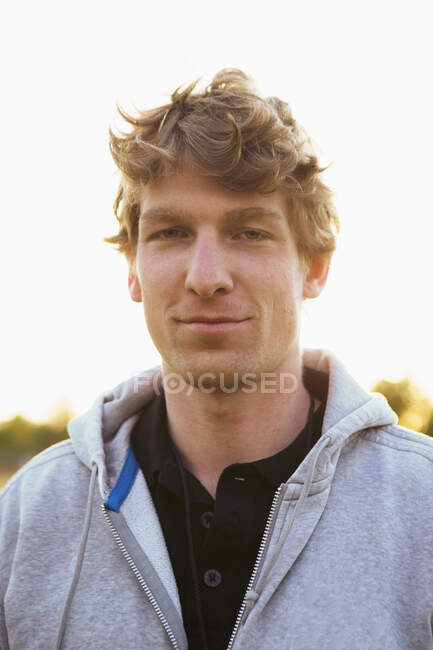 Retrato de un joven futbolista confiado con chaqueta encapuchada al aire libre - foto de stock