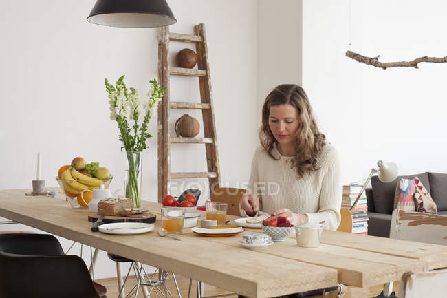 Mid adult woman having breakfast at table — Stock Photo