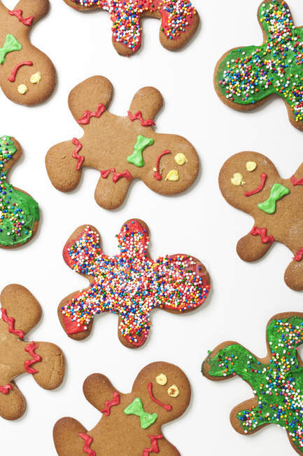 Various Decorated Gingerbread Men Cookies Arranged On White