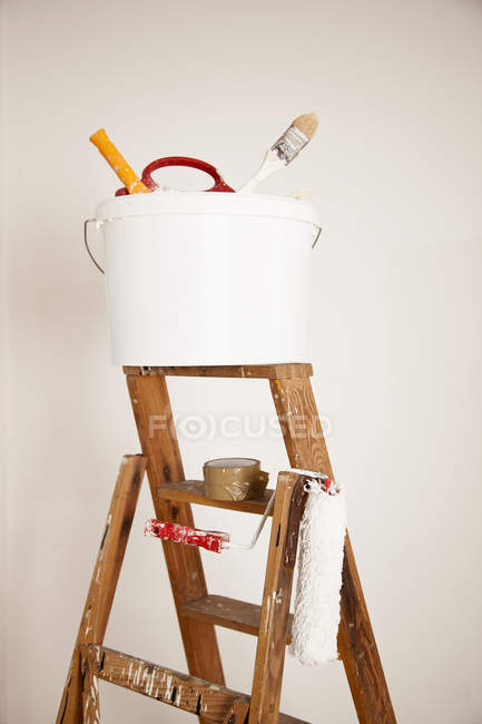 Secchio bianco con rifornimenti di vernice e rullo di vernice sulla scala a gradini — Foto stock