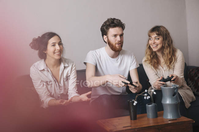 Excited young friends playing video games at home — Stock Photo