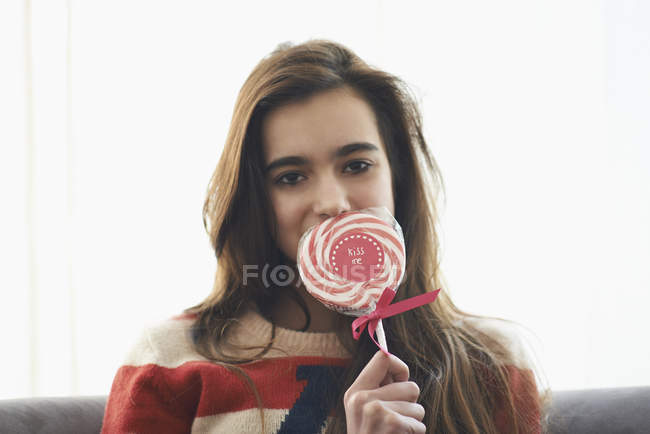 Retrato de chica romántica cubriendo la boca con piruleta en casa — Stock Photo
