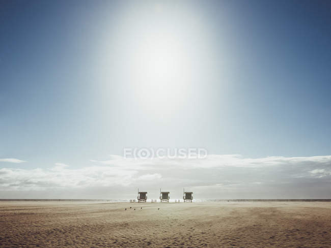 Vista a distanza di rifugi bagnino in spiaggia contro il cielo nella giornata di sole — Foto stock