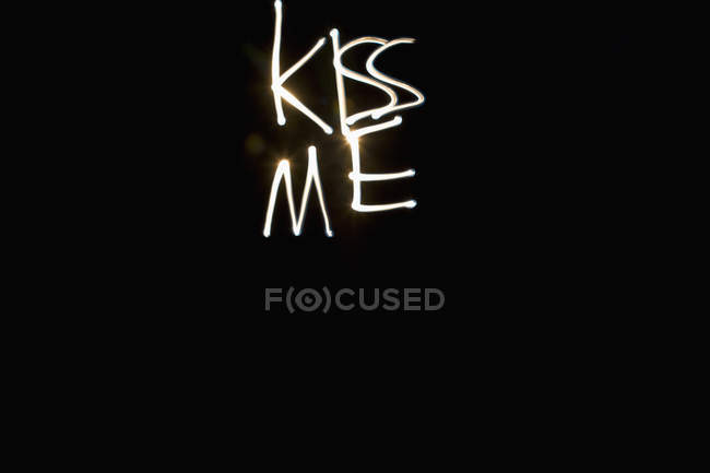 Scatto a lunga esposizione di scritte KISS ME scritte con luce su nero — Foto stock