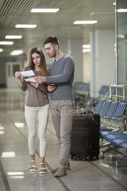 Pareja joven leyendo entradas en el aeropuerto - foto de stock
