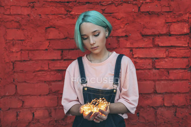 Teenage Girl Holding Illuminated String Lights While Standing Against Brick Wall Focus On Foreground Fashion Stock Photo 178110884 - String Lights Brick Wall