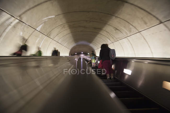 Vista a basso angolo delle persone sulla scala mobile nella stazione ferroviaria sotterranea — Foto stock