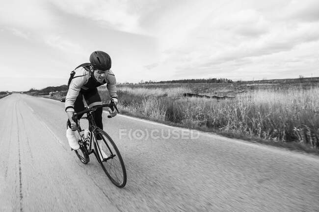 Movimiento borroso de ciclista montar en bicicleta en el campo camino por campo contra el cielo - foto de stock