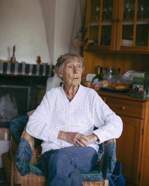 Thoughtful senior woman sitting on armchair at home — Stock Photo