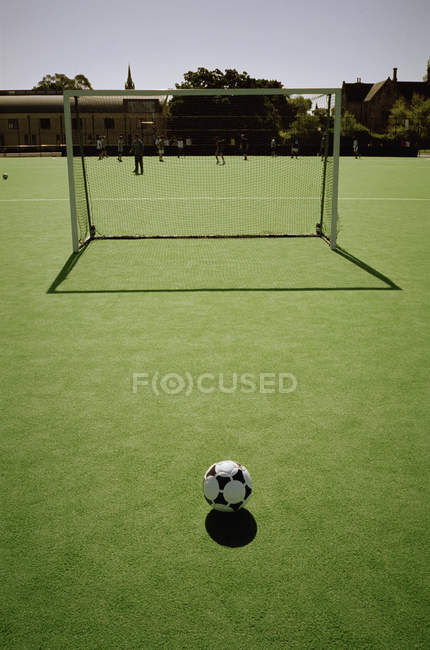 Футбольний м'яч перед собою мету з гравцями навчання у фоновому режимі — стокове фото