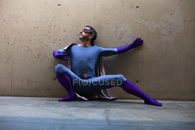 Supereroe maschio accovacciato contro il muro — Foto stock