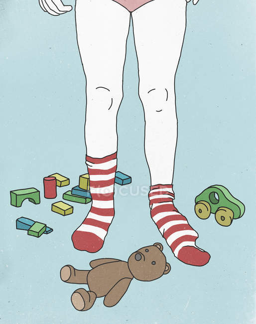 Baixa seção de menina em meias listradas cercada por brinquedos — Fotografia de Stock