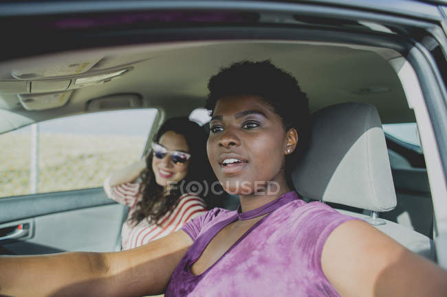 Lächelnde junge Frau schaut weg, während sie mit Freundin im Auto sitzt — Stockfoto