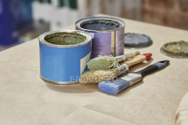 Close-up of paint cans and paintbrushes on workbench — Stock Photo