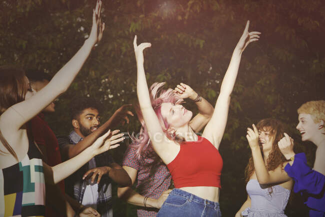 Возбужденная женщина танцует с друзьями во дворе во время вечеринки — стоковое фото