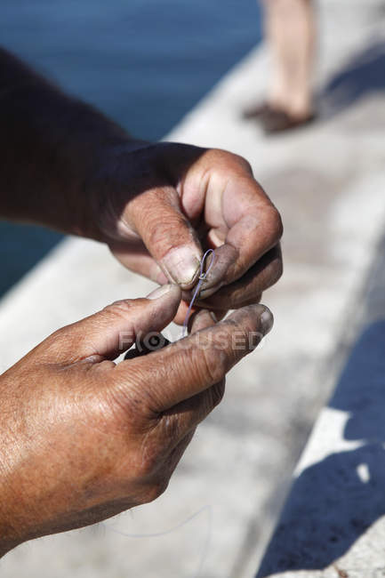 Crop male hands tying a fishing line to hook — Stock Photo