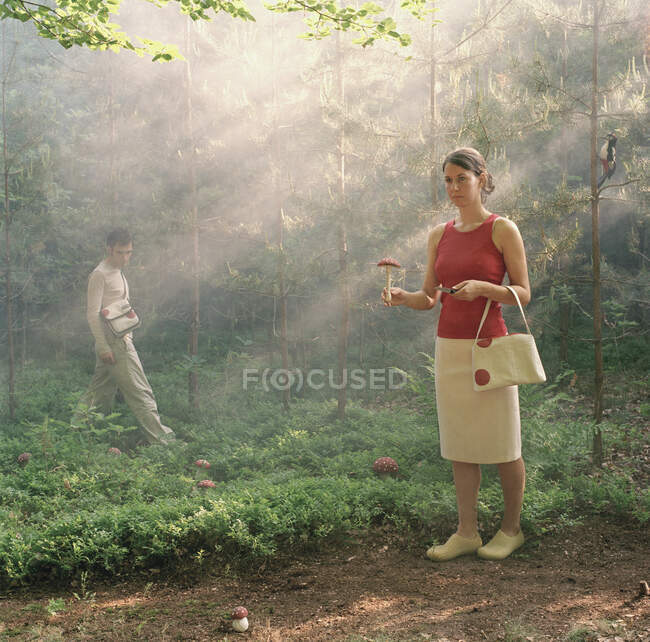 Una mujer posando con un hongo y un cuchillo en un bosque - foto de stock
