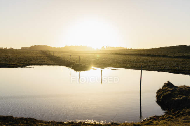 Scenic view of pond in field against sky during sunrise — Stock Photo