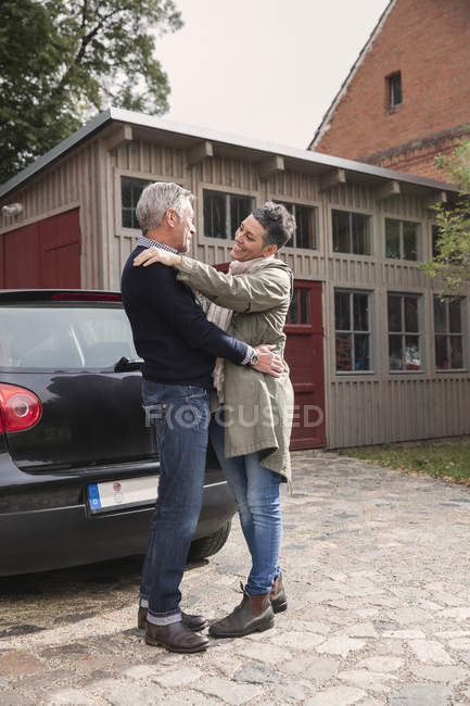Щаслива пара, підтримуючи в автомобіль проти будинок — стокове фото