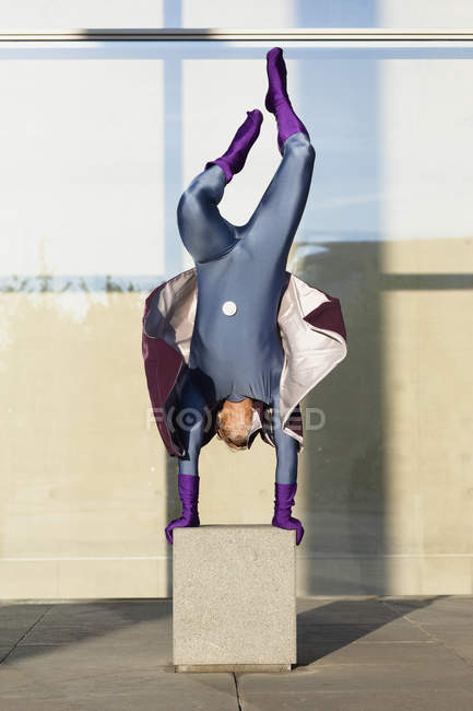 Supereroe facendo handstand su calcestruzzo contro muro di vetro — Foto stock