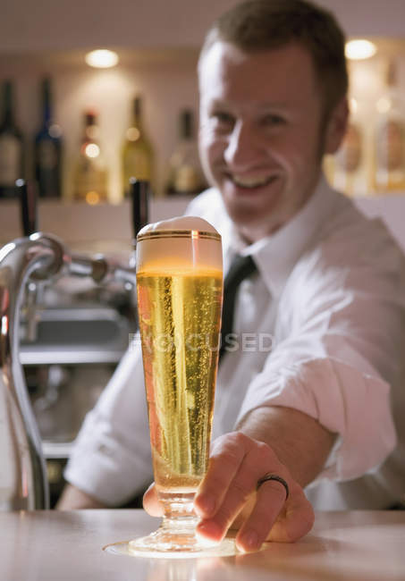 Bartender serving a glass of beer — Stock Photo