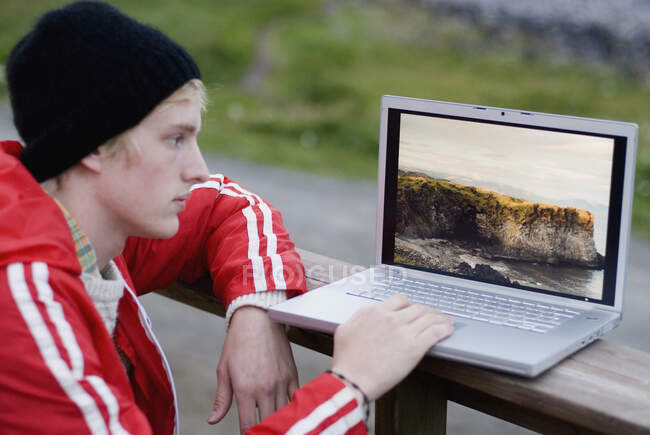 Hombre joven usando el ordenador portátil al aire libre - foto de stock